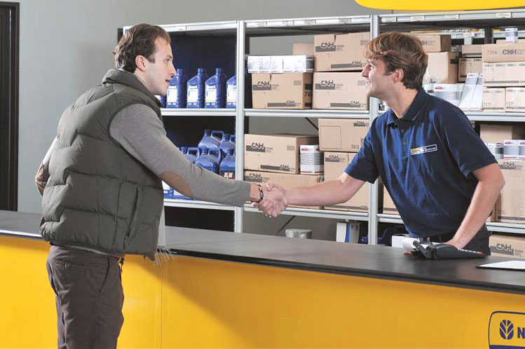 New Holland parts employee shaking hands over parts counter